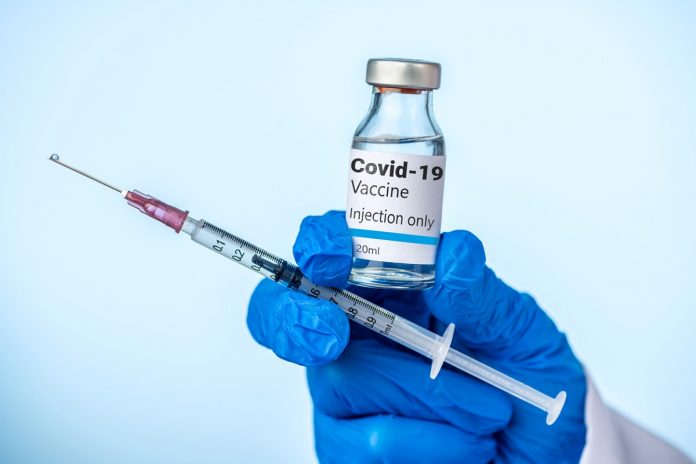 Doctor or nurse is holding the Covid-19 vaccine and syringe with her blue glove. Szczepienie covid-19 Johnson&Johnson